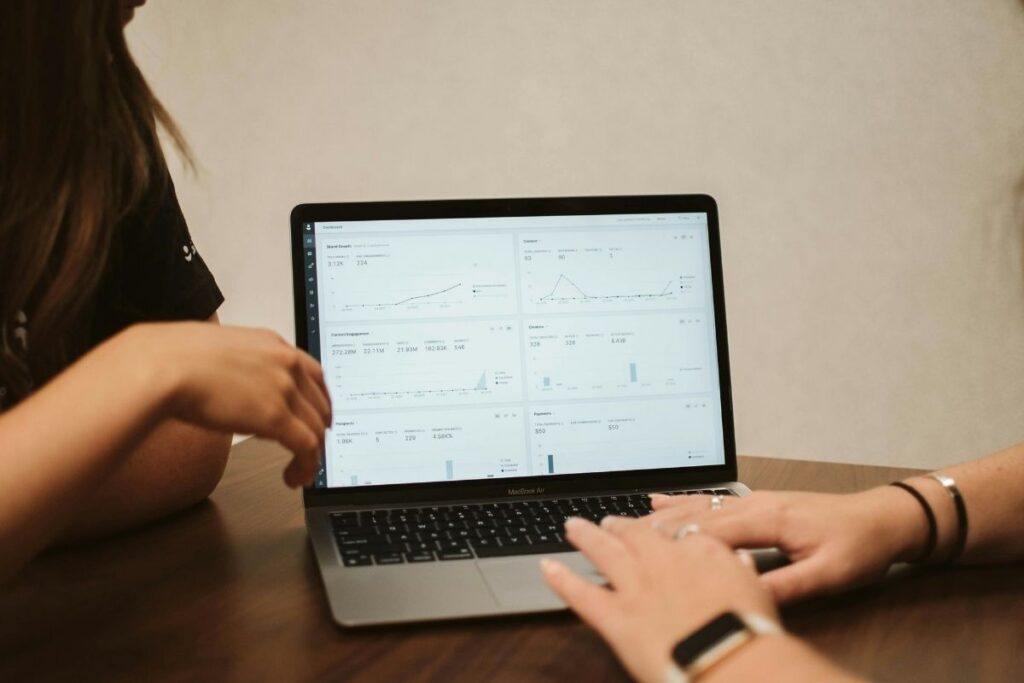 Two people working together on a single laptop.